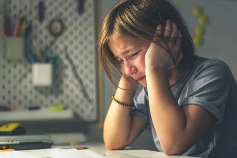Upset schoolgirl doing lessons, her homework. learning difficulties Stock Photos