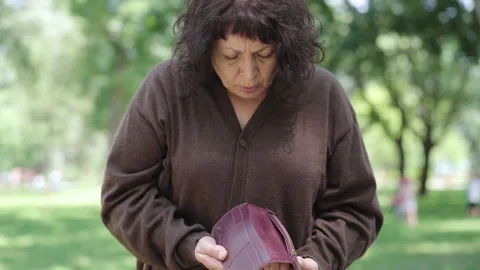 Upset senior retiree opening empty wallet and shaking head approaching it to Stock Footage 143025010