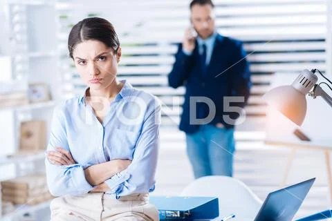 Upset woman pouting her lips while sitting with her arms crossed Stock Photos