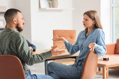 Upset young couple discussing problems with family mediator at table in offic Photos