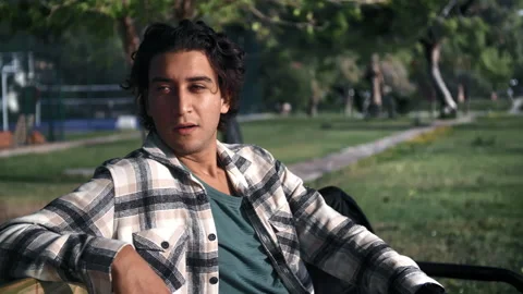 Upset young Hispanic man waiting someone something at summer sunny park nature Stock Footage 219959626
