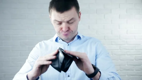 Upset young man holding empty wallet over white background Stock Footage 104612333