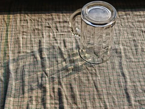 Upside Down Clear Glass Mug with Handle on Textured Fabric Tablecloth Photos