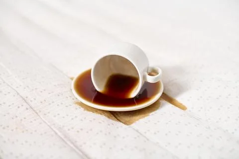 Upside-down coffee cup on white fabric with spilled liquid Stock Photos