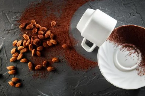 Upside-down cup with cocoa powder and cocoa beans on a dark background. Top view Photos