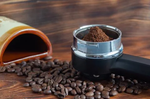 An upside down cup with coffee beans. Coffee machine horn with ground coffee. Stock Photos