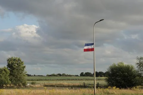 Upside-down Dutch flag with fields in the background Stock Photos
