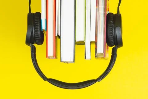 Upside down headphone and books on yellow background Stock Photos