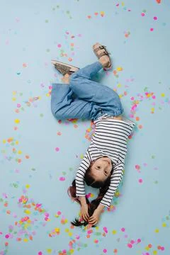 Upside down image of a smiling pretty girl, lying on a blue floor. Stock Photos