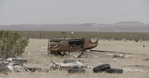 Upside Down Rusted Car And Junk in Yard of Desert House - Pan Across Stock Footage 89943153
