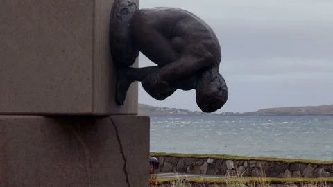 An upside down statue of man in foreground with sea in background Stock Footage 92637918