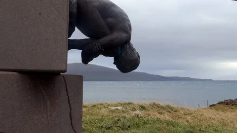 An upside down statue of man in foreground with sea in background Stock Footage 92637927