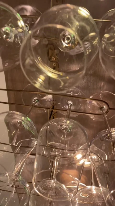 Upside-down wine glasses on brass rails beneath shelf with warm interior light Stock Footage 341664611