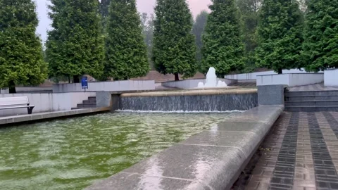 Upward camera move along steps beside a cascading park fountain Stock Footage 295368818