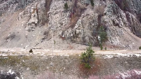 Upward crane shot along side of mountain with rocky exterior and trees on ove Stock Footage 125278021