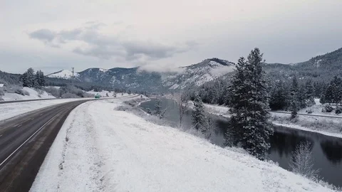 Upward crane shot over river and train tracks surrounded by snow and evergree Stock Footage 125491239