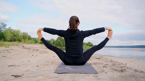 Upward Seated Wide Angle Pose. A girl in an elongated angle pose sits on the Stock Footage 123398634