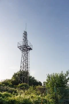 Upward view of abandoned radio communication antenna tower with plants around Stock Photos