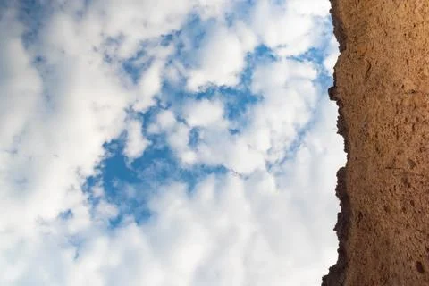 Upward view, blue sky with clouds and mountains on a clay background. Stock Photos