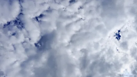 Upward view of dramatic white and grey clouds moving across blue sky, creating Stock Footage 341422231
