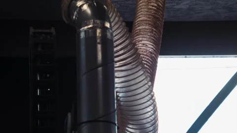 Upward view of a dust extraction hose and workshop ceiling structure inside an Stock Footage 334996978