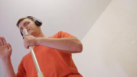 Upward View Of Man Singing Into Mop Handle While Dancing With Headphones Stock Footage 319914899