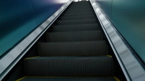 Upward view of a modern illuminated escalator with textured side panels and Stock Footage 310347009