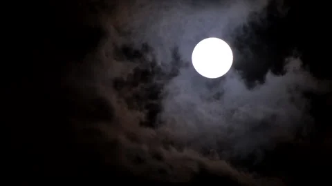 Upward view of round full moon in dark night sky as gloomy clouds pass by 库存影片 320663589