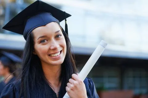 Successful graduation from university. Smiling beautiful Asian girl  university or college graduate standing with diploma over university at  background. Stock Photo