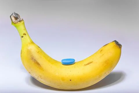 Upwards yellow banana with a blue erection pill, concept of the effect of the Stock Photos