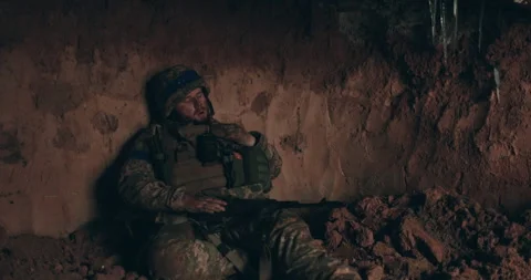 A Urain soldier sits on the bare ground in a dugout with a rosary Stock Footage 261748483