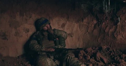 A Urain soldier sits on the bare ground in a dugout with a rosary Stock Footage 261748513