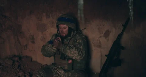 A Urain soldier sits on the bare ground in a dugout with a rosary Stock Footage 261748810