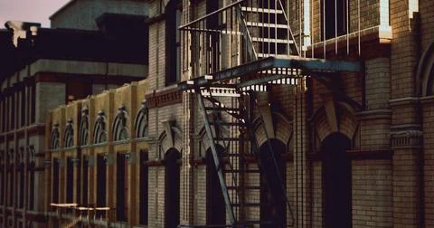 Urban architecture featuring a fire escape at dusk near city buildings Ilustración de archivo