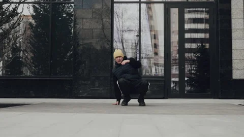Urban breakdancer executing dynamic moves on a concrete surface, framed by Stock Footage 274429860