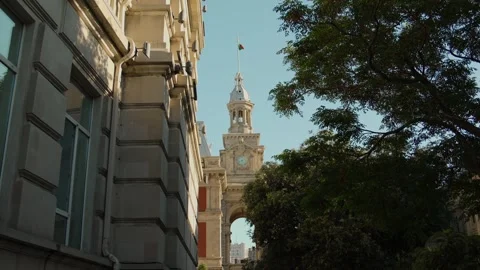 Urban Clock Tower with Fluttering Flag on a Sunny Day Stock Footage 338244222