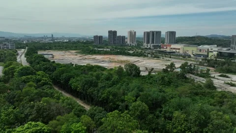 Urban development site viewed from above near city skyline with lush greenery Stock Footage 311986773