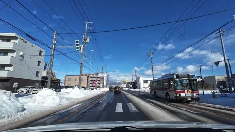 Urban driving with mountain backdrop on wet road in Hakodate winter Video stock 333069448