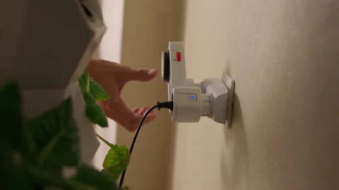 Urban farmer inserting smart plug with power button into wall socket, connecting Stock Footage 317395804