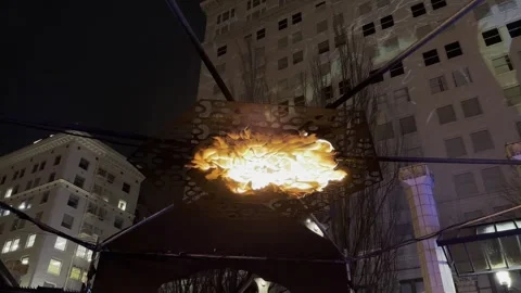 Urban flame installation glowing beneath metal structure at night in Portland Stock Footage 326862850