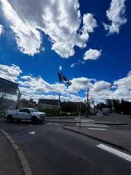 Urban intersection under dramatic blue sky with fluffy clouds, pickup truck.. 写真素材