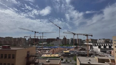 Urban Landscape with Multiple Cranes Constructing a Stadium Under a Chaning Sky Stock Footage 336556282