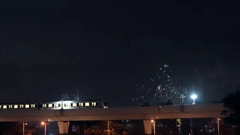 Urban light rail train leaving station with fireworks in the night sky Stock Footage 331768821