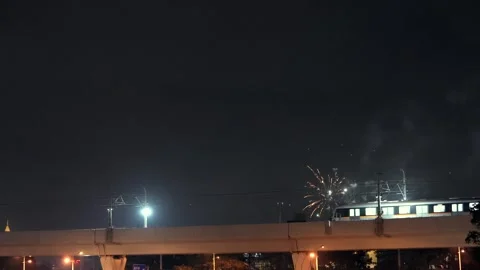 Urban light rail train leaving station with fireworks in the night sky Stock Footage 331768822