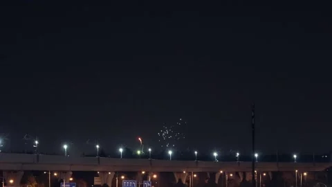 Urban light rail train leaving station with fireworks in the night sky Stock Footage 331768850