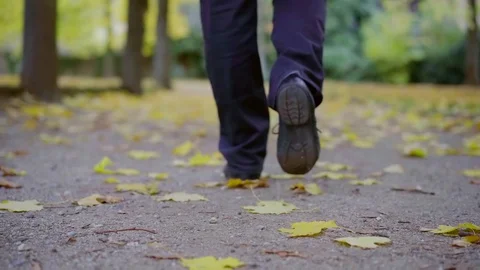 Urban man walking on the streets in fall, leaves lying around on asphalt. 库存影片 99556056