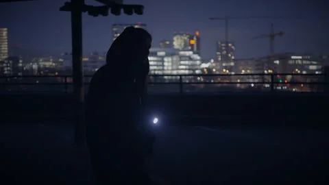 Urban night explorer with flashlight scans city skyline, delving into 库存影片 280319729