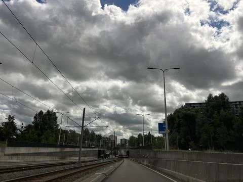 Urban railway corridor beneath dramatic storm clouds with overhead power lines Stock Photos