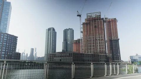 Urban river flows in front of high rise residental apartments and new skyscr Stock Footage 243811534