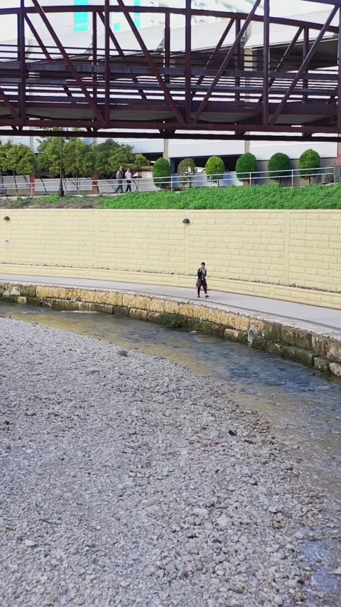 Urban River Walk – Panning Shot of Pedestrian Bridge and City Park – Vertical Stock Footage 329069502